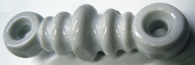 Figure 2 — A ribbed ceramic dogbone strain insulator — the BOM's end-insulator family (Section 3), shaped with a long creepage path specifically to resist the surface tracking and arcing discussed in Section …
